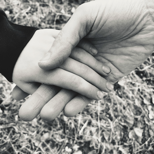 Ein Foto in schwarzweiß, das die Hand einer Mutter zeigt, die liebevoll die Hand ihres Kindes hält