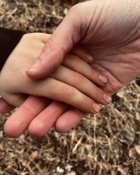 Hände_Oktober24 Foto einer Erwachsenenhand, die zärtlich die kleinere Hand eines Kindes hält.
